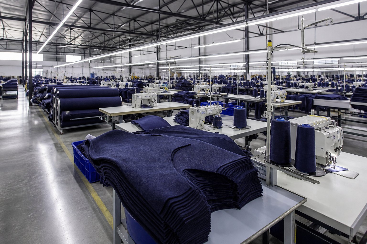 Referência visual de linha de confecção industrial com malha azul-marinho. Não é um retrato da unidade de Golães.